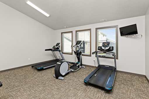 A room with a treadmill, elliptical trainer and a stationary bike.