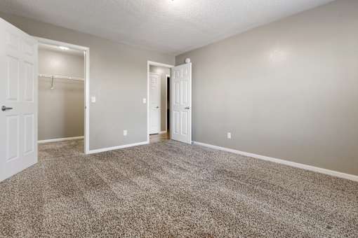 A room with carpeted floor and two doors.