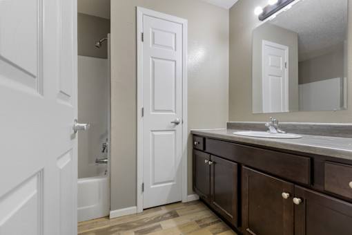A bathroom with a white door and brown cabinets.