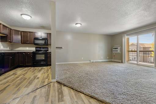 A large open living space with a kitchen area to the left and a doorway to another room to the right.