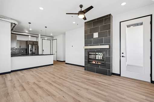 A modern kitchen with a wood floor and a fireplace.