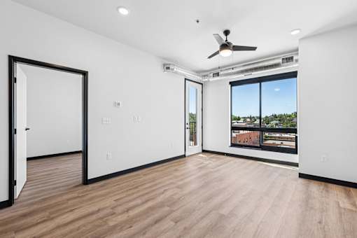 A room with a ceiling fan and a window overlooking a cityscape.
