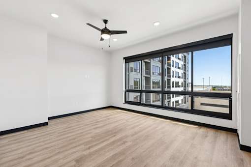 A room with a ceiling fan and a large window overlooking a cityscape.