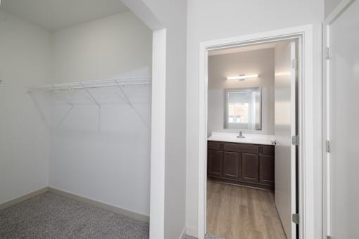 A white bathroom with a wooden vanity and a mirror.