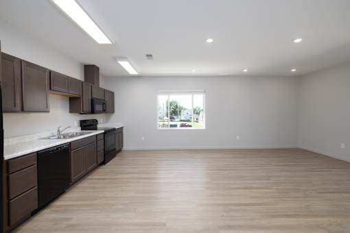 A kitchen with brown cabinets and a window overlooking a green landscape.