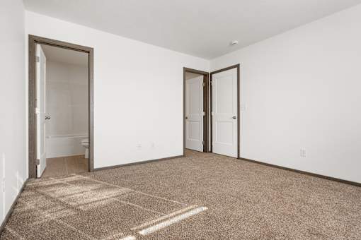 A room with a carpeted floor and two doors.