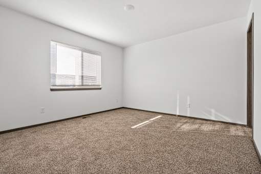 A room with a carpeted floor and a window.