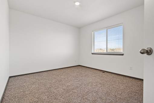A room with a carpeted floor and a window.
