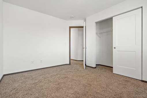 A carpeted room with a white door and a white wall.