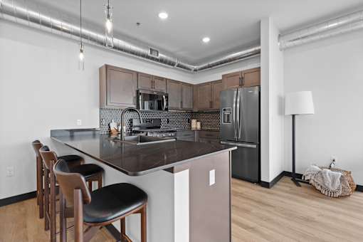 A kitchen with a refrigerator, stove, and bar stools.