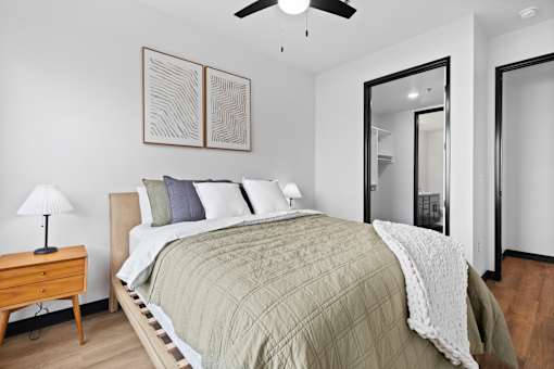 A bedroom with a bed, a nightstand, a lamp, and a ceiling fan.
