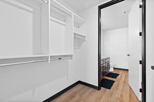 A white hallway with a black door and a black mat on the floor.