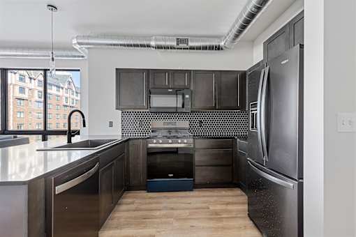 A modern kitchen with a stainless steel refrigerator and black cabinets.