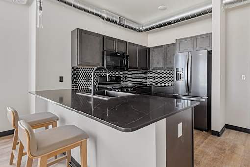 A kitchen with a black counter top and a refrigerator.