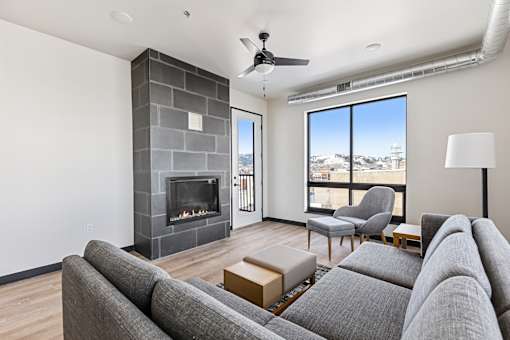 A living room with a grey couch and a fireplace.