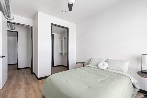 A bedroom with a bed, nightstand, and mirrors.