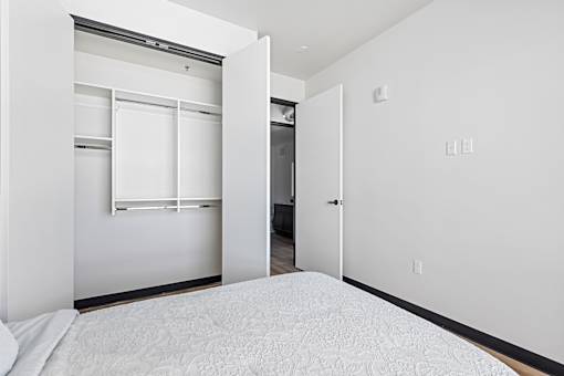 A white bedroom with a bed and a closet.