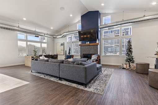 A modern living room with a grey sofa and a wooden floor.