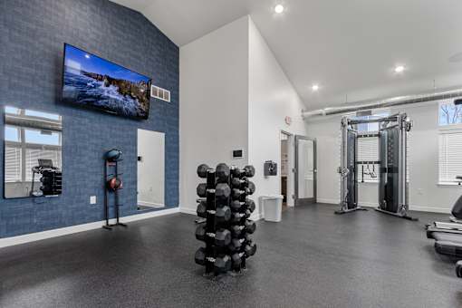 A gym with a television on the wall and various exercise equipment.