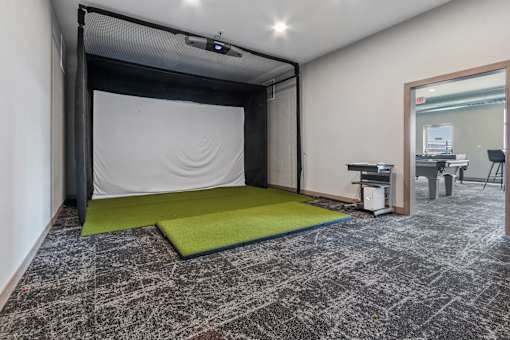 A room with a black and white patterned carpet and a green mat in front of a black screen.