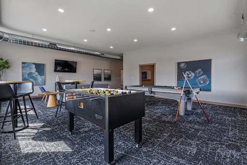 A room with a pool table and a foosball table.