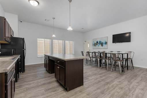 A kitchen with a black fridge and a dining table with chairs.