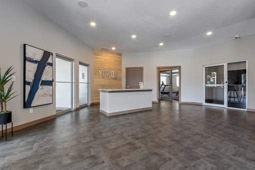 A reception area with a white counter and a plant on the left.