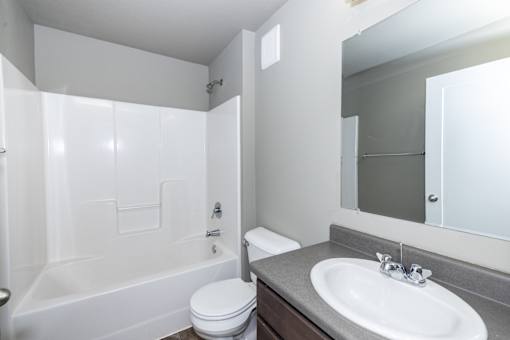 A white bathroom with a toilet, sink, and bathtub.