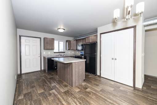 A kitchen with a white door and a wooden floor.