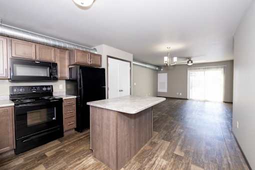 A kitchen with black appliances and wooden floors.