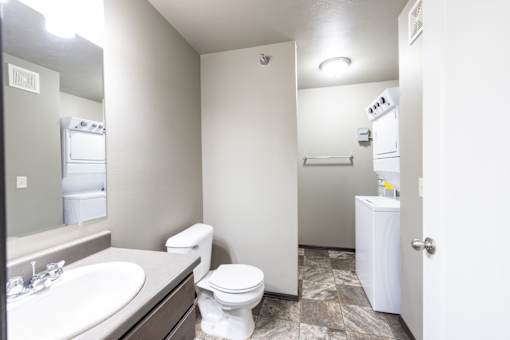 A bathroom with a toilet, sink, and a white cabinet.