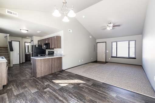 A spacious living room with a kitchen area in the background.