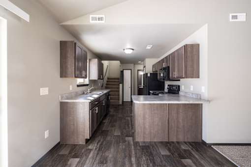 A kitchen with wooden floors and a black refrigerator.