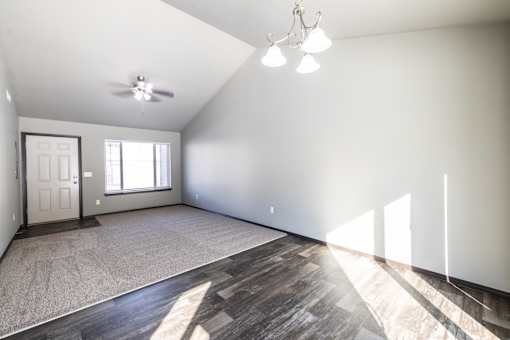 A spacious room with a ceiling fan and a door.