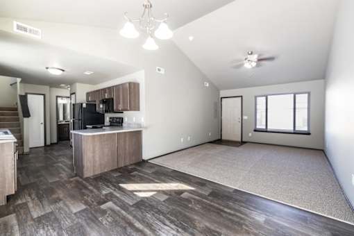 A spacious living room with a kitchen area in the background.
