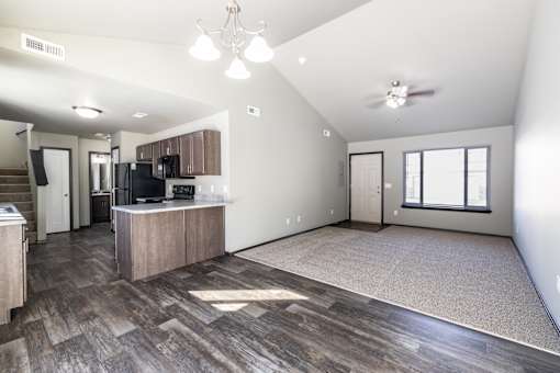 A spacious living room with a kitchen area in the background.
