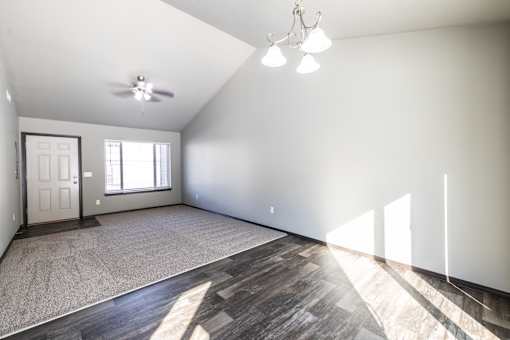 A spacious room with a ceiling fan and a door.