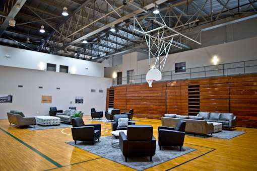 A basketball court with a hoop and a variety of seating.
