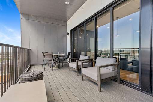 A balcony with a table and chairs overlooking a cityscape.