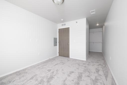 A room with a carpeted floor and a wooden door.