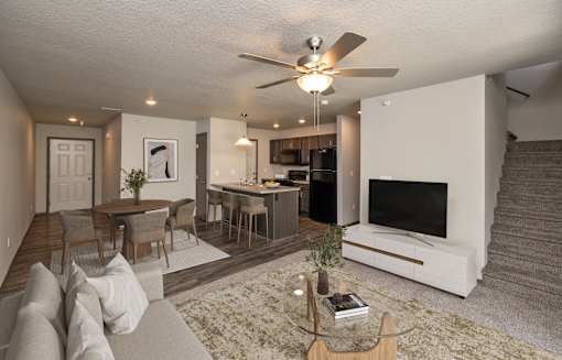 A living room with a couch, a coffee table, a television, and a staircase.