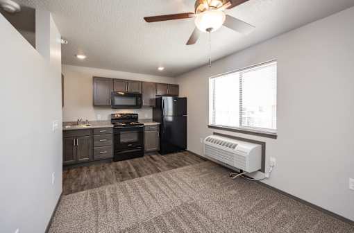A well-lit, empty room with a kitchenette and a window.