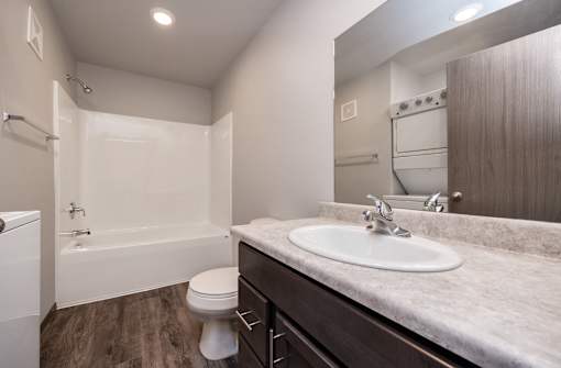 A white toilet is in a bathroom with a sink and a bathtub.