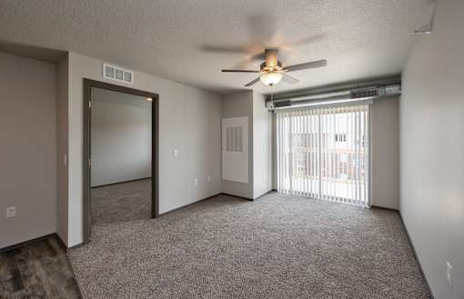 A room with a ceiling fan and sliding glass doors.