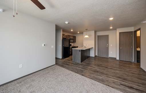 A spacious room with a kitchen area and a ceiling fan.