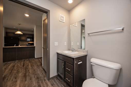 A bathroom with a toilet, sink, and mirror.
