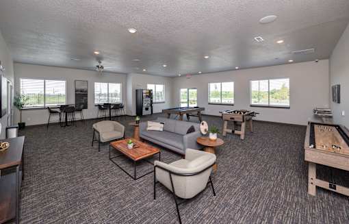 A spacious living room with grey carpeting and furniture.