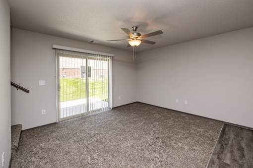 A room with a ceiling fan and sliding glass doors.