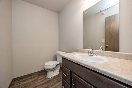 A bathroom with a toilet, sink, and mirror.