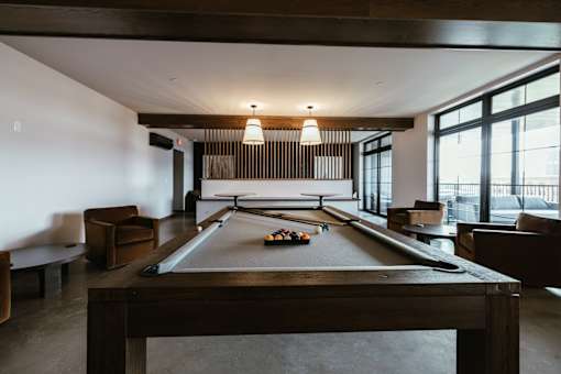 A pool table is in the middle of a room with a couch and a chair.